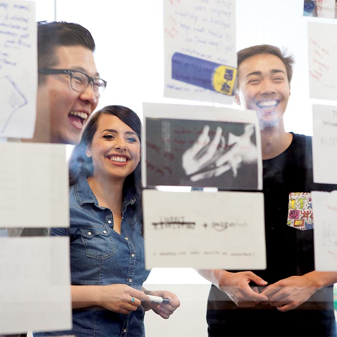 Students laughing while looking at a wall of papers